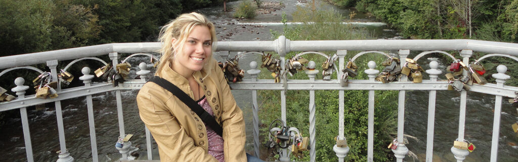 Anne is seated on a bridge covered in thousands of locks.