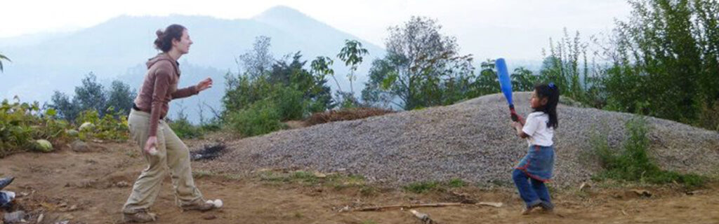 Christine throws a ball to a young girl who is waiting to bat