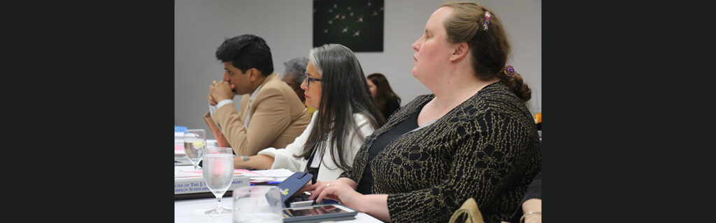 Christie Gilson (R) taking notes at board meeting next to another board member.