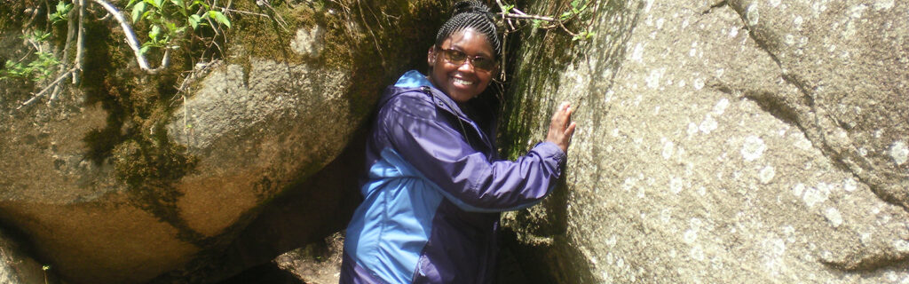 Maegan poses for a photo between two large rocks.