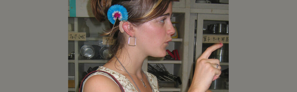 A Deaf girl is in the middle of a sign and appears to be asking a question of someone out of the frame of the picture.