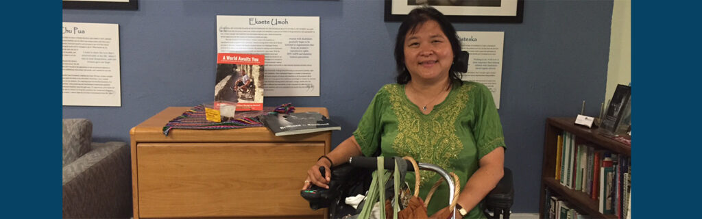 Jeanette, seated in a power wheelchair, at the MIUSA office.