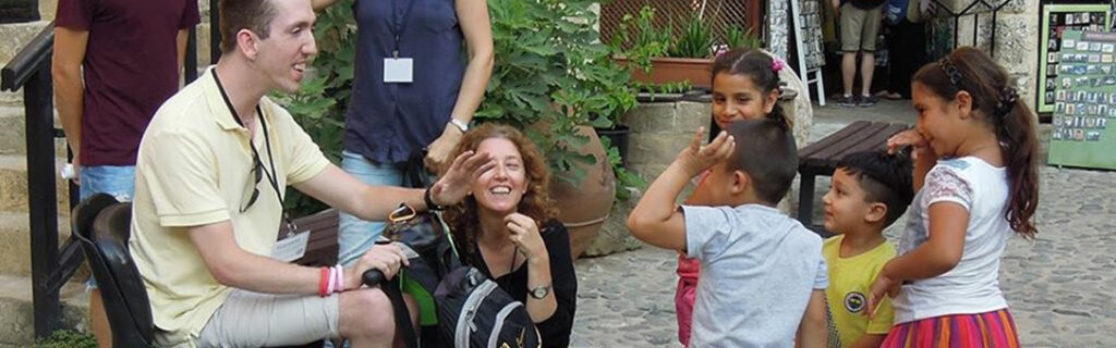 Garrett Brumfield in his scooter interacts with young children in a Cyprus street.