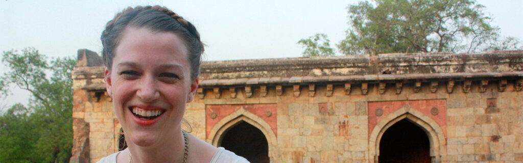 Volunteer to India smiles widely with arched entryways behind