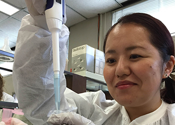 Mayuko, a Japanese woman, in science lab putting liquids from a syringe into a tube. 