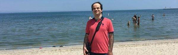 Sameh stands on the beach with the ocean in the background.