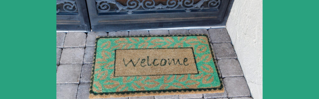 Green welcome mat in front of a door reads "Welcome"