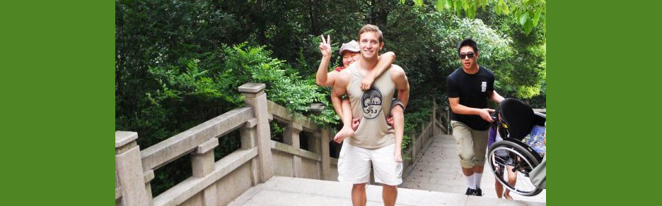 A college student with a physical disability gets lifted piggyback up stairs in China while her friends carry up her empty wheelchair