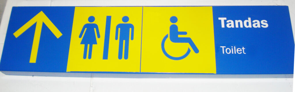 Blue and yellow sign indicating lavatory. Text reads "Tandas - Toilet"