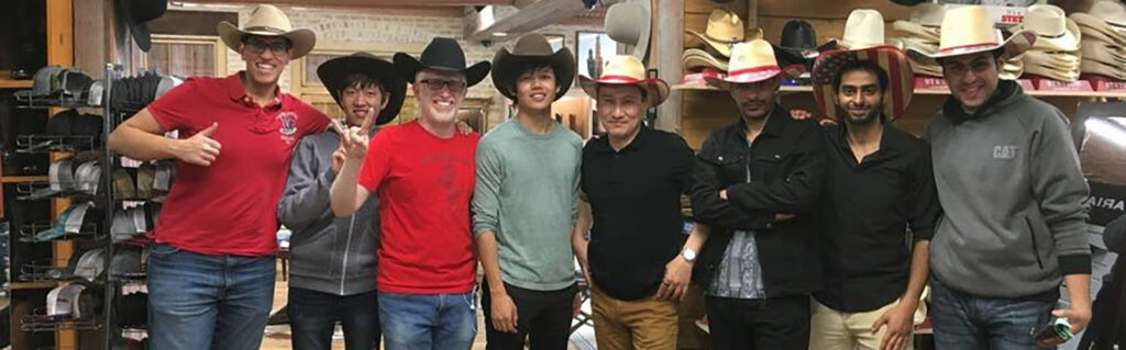 Ahmed standing with a large group of friends in a cowboy store all wearing cowboy hats.
