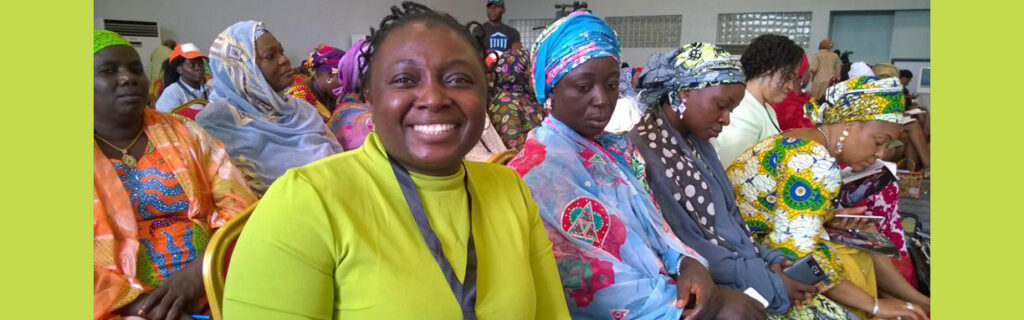 Lois in foreground seated in audience of African women all wearing colorful dresses