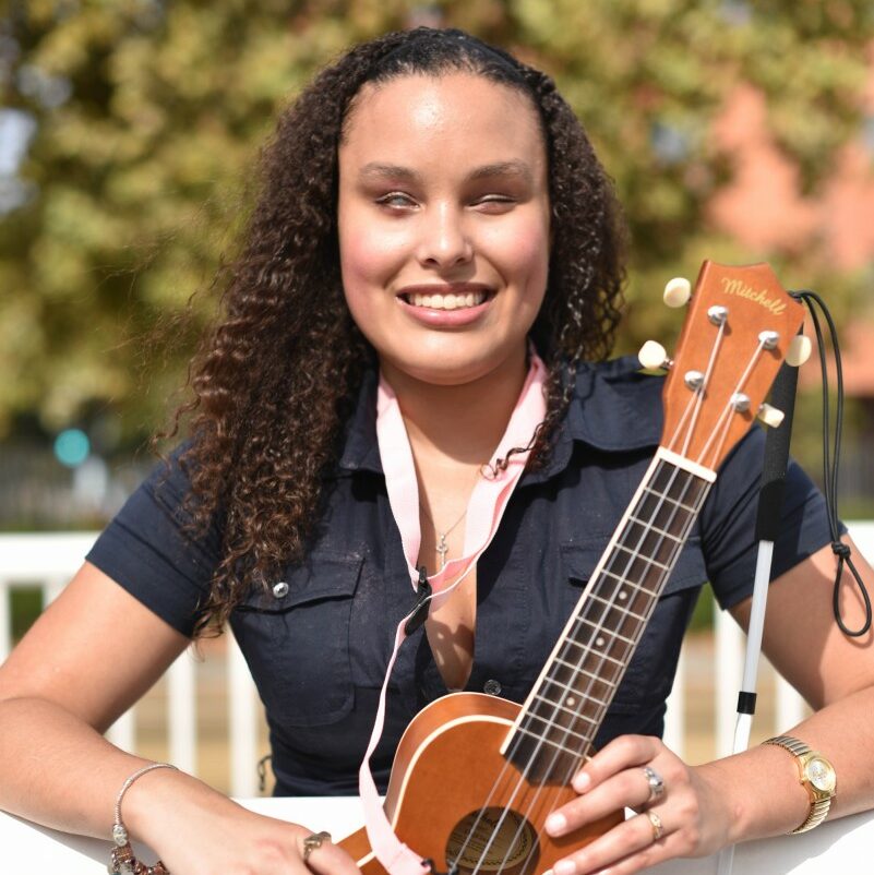 Portrait of Precious smiling at the camera holding instrument.