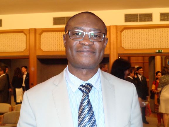 Portrait of Godwin during a visit to Europe. He wears a tan suit and striped tie.