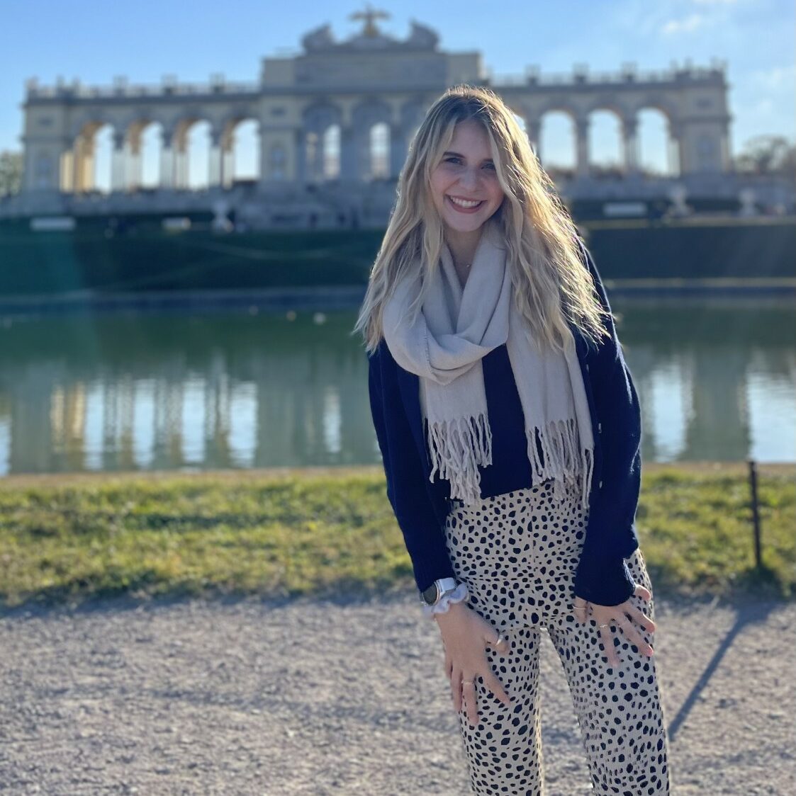 Kristen Popham stands smiling in front of a monument at the Schönbrunn Palace Gardens in Vienna, Austria.