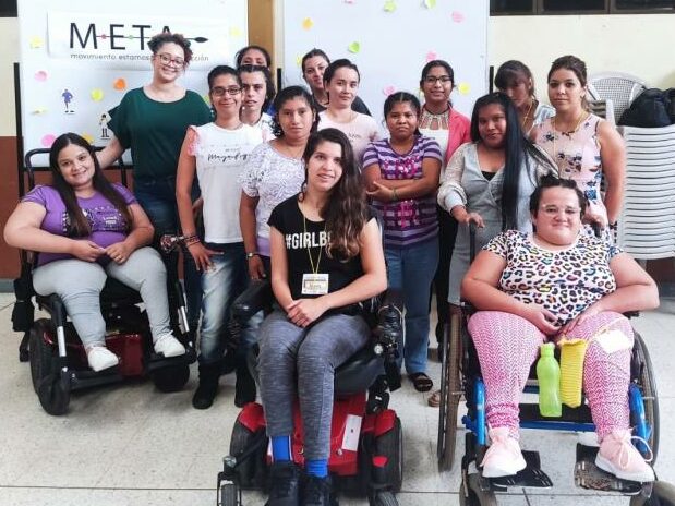 Fifteen women with various disabilities, some using wheelchairs, pose together and smile facing the camera during WILD-Costa Rica.