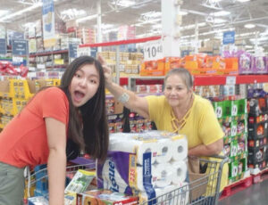 Azzaya and host mom in a grocery store pushing a full cart.