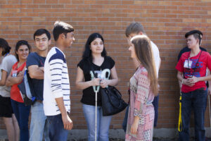 Group of students standing outside of a school talking to one another. 