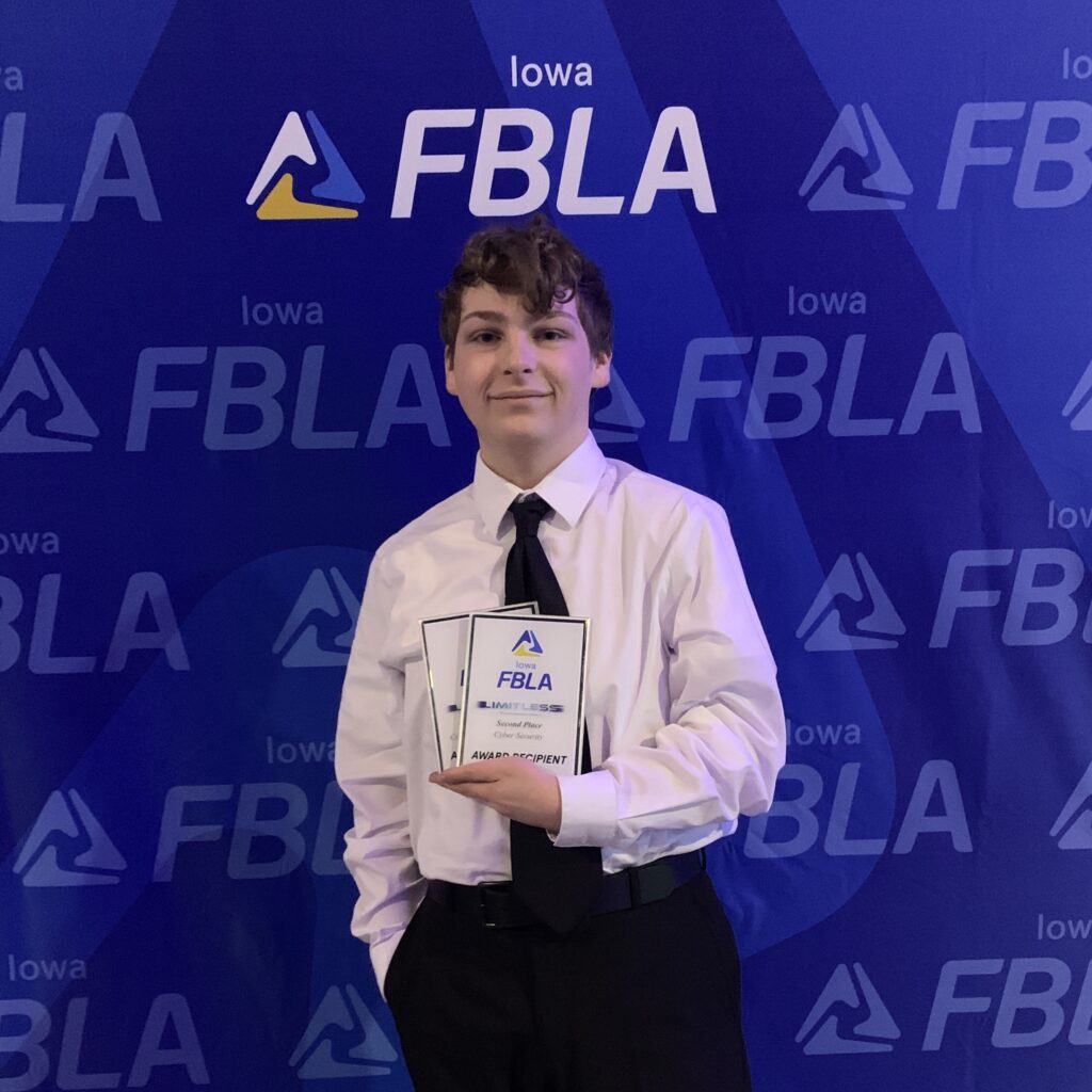 High school student in formal attire holding an award plaque. Backdrop says "Iowa FBLA".