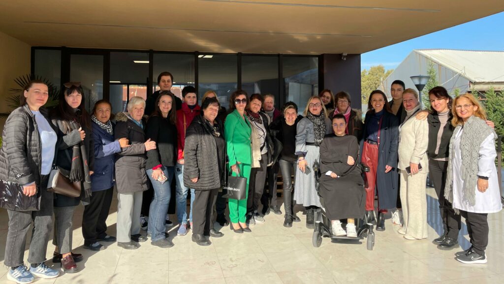 20 people standing outside of a building smiling for a group photo.