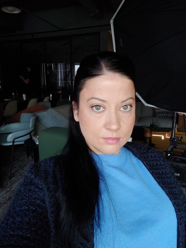 Professional photo of a Caucasian woman with dark hair and green eyes wearing a blue top and a dark cardigan