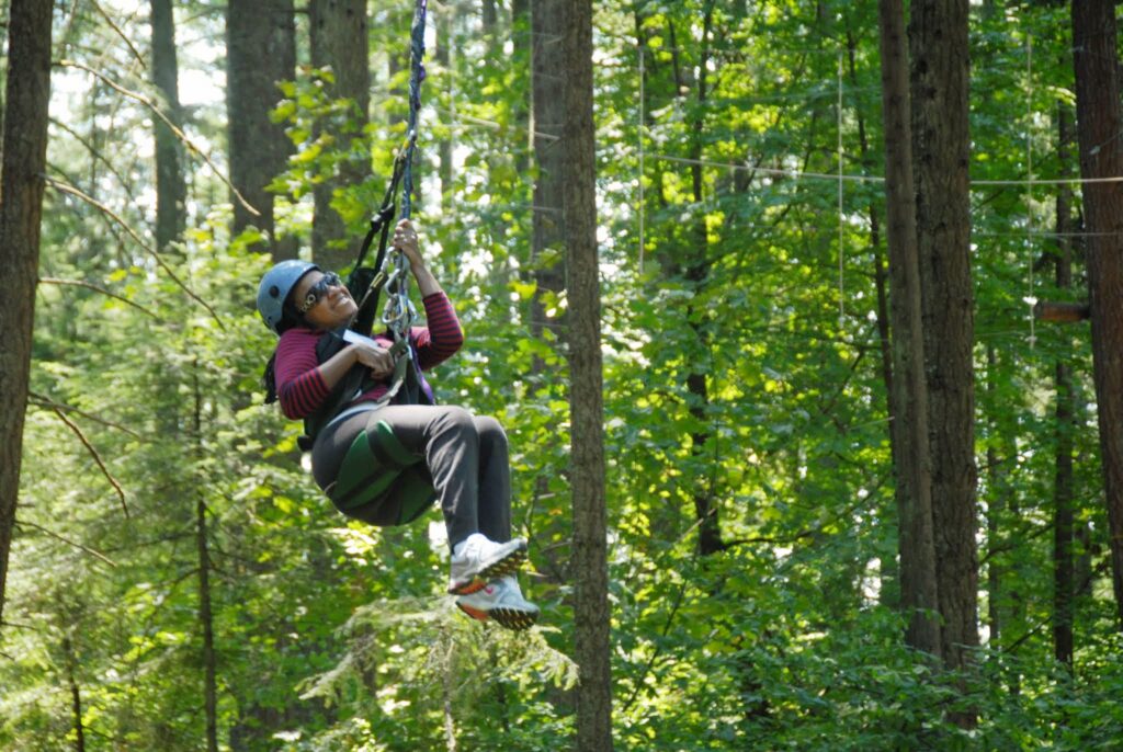 WILD delegate swinging from the trees at the Ropes Challenge Course
