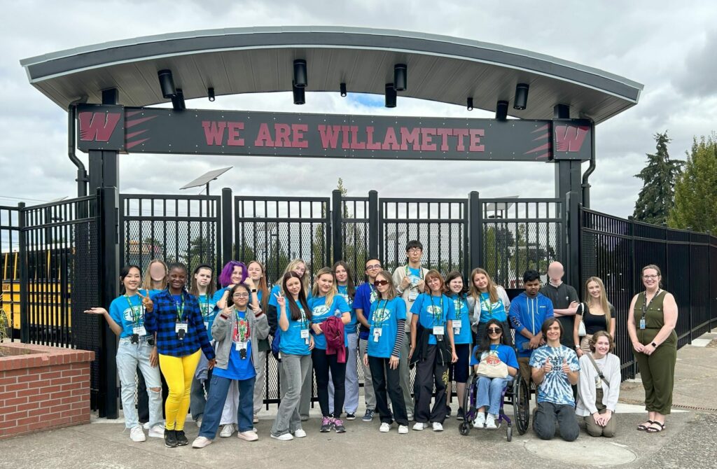 Group photo of students smiling outside under a gate with the text We Are Willamette.