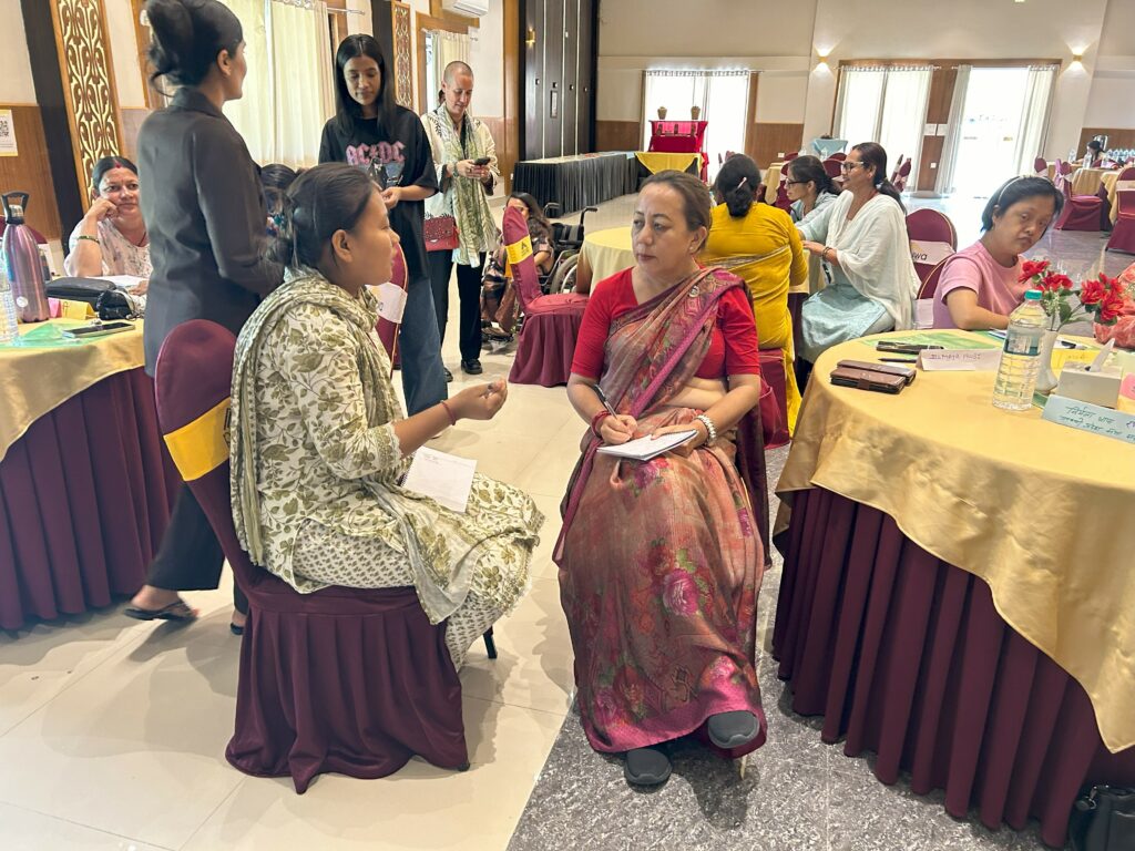 Two Nepali women wearing traditional saris sit and converse during a workshop.