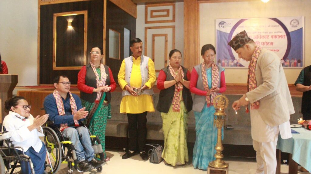 Six Nepali people clapping and looking towards the lighting of a tall object by a government representative.