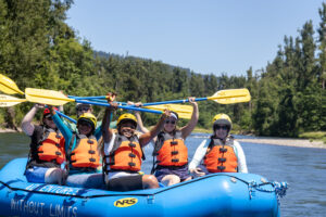 WILD delegates, interpreters and staff raise paddles in the air while river rafting.