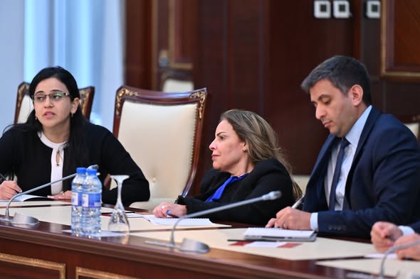 Asia seated behind a desk with other members of Parliament in Jordan.