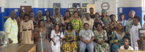 All 22 WILD-Benin training participants and their personal assistants pose for a group photo in a large classroom.