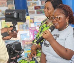 WILD Delegate Marlise Montcho speaks into a microphone with a camera recording her speech.